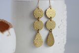 Brass earrings with circular and teardrop shapes on a white background