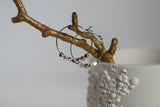 Gold branch with silver hoop earrings on a white surface