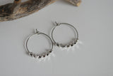 Silver hoop earrings with beaded detailing on a light gray background