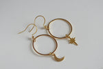 Gold hoop earrings with moon and star charms on a white background