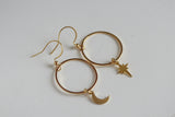 Gold hoop earrings with moon and star charms on a white background